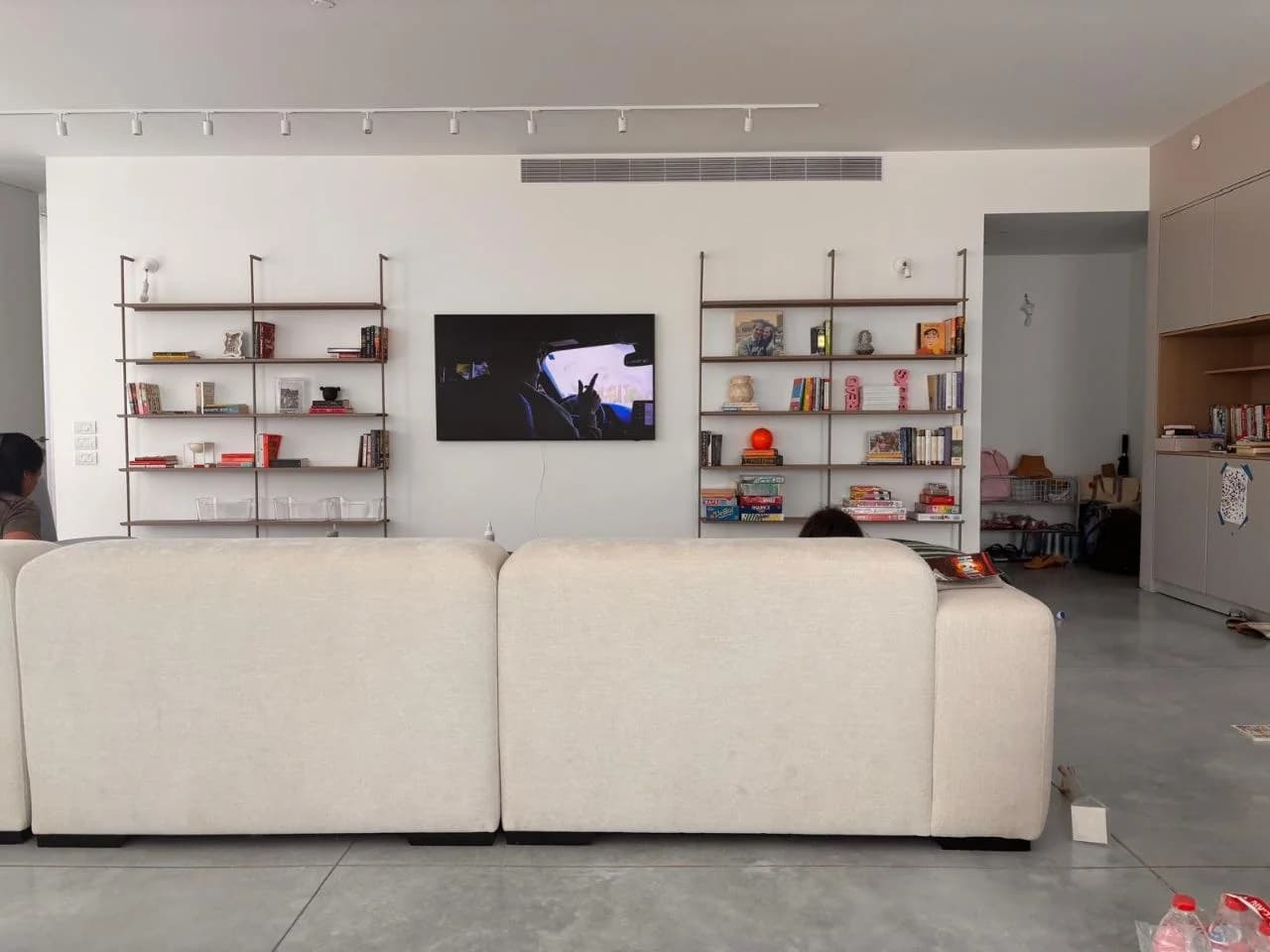 שתי ספריות מתכת חומות של Cubix משני צדי טלוויזיה על קיר לבן, ביום ההתקנה